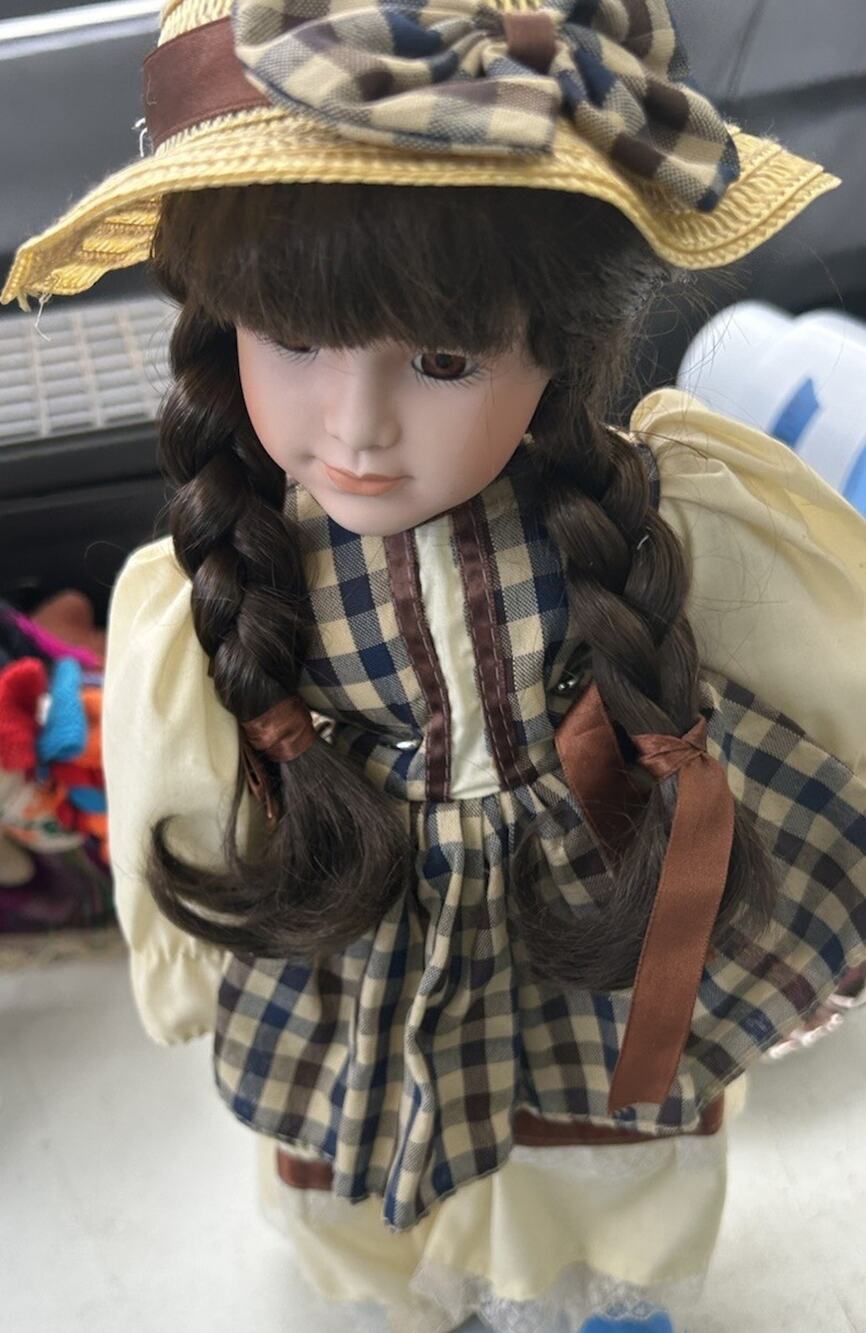 collectible porcelain doll dressed in a beige and brown checkered dress